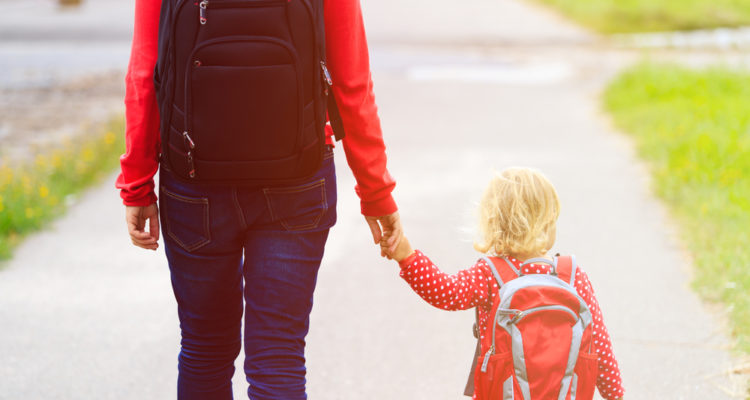 mom, holding, kids, hand, who, is, wearing, a, backpack